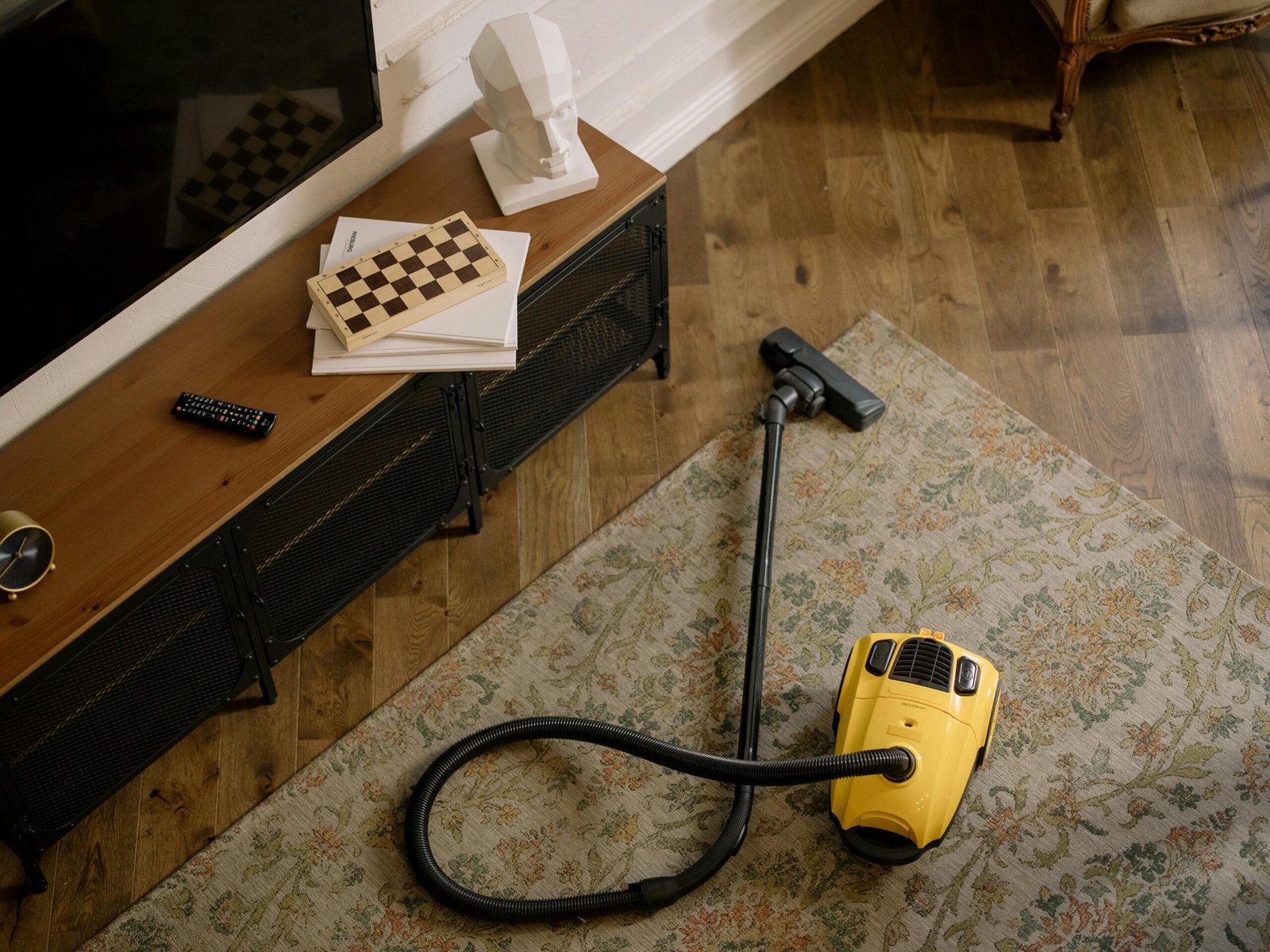 Warm living room scene featuring a yellow vacuum on a floral carpet with a vintage vibe.